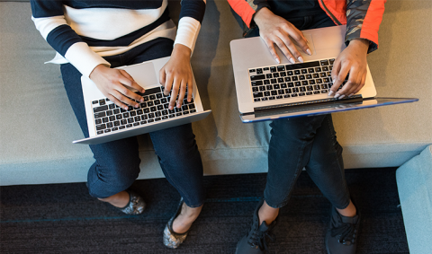 Two people working on laptops from above