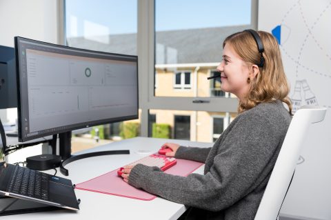 Sam sat at her desk with a headset on looking at her monitor.