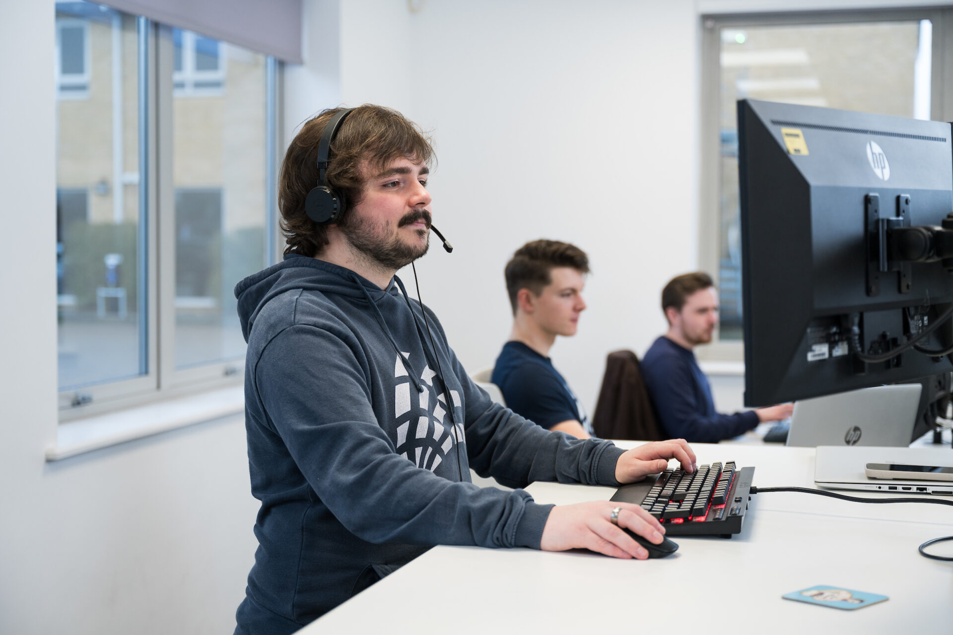 Liam working at standing desk, Brenden and Jordan behind