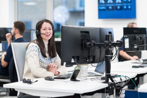 Jess speaking into headset at her desk in the Breakwater office.