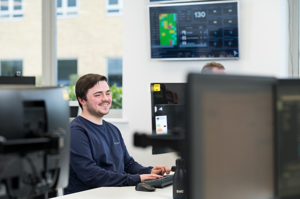 Liam sitting at his desk, focused on his computer screen in the office.