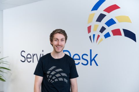 Leon in front of a Service Desk Sign on the wall.