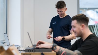 Richard and Bryce engaged in a discussion while working on a laptop in an office.