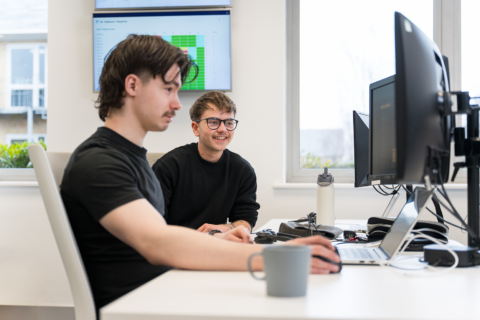 James and Alec sat at James' desk looking at his monitor in the office